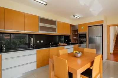 a kitchen with wooden cabinets and a wooden table at Private pool and sea view - Tropical Villa in Arco da Calheta