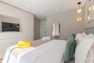 a white bedroom with a large bed with a yellow towel on it at Casa da Ilha in Funchal