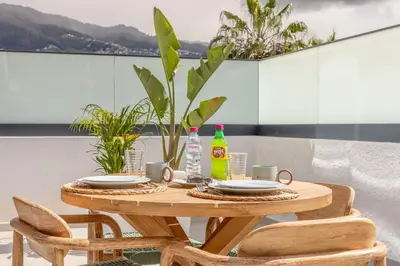 a wooden table with plates and drinks on a balcony at Casa da Ilha in Funchal