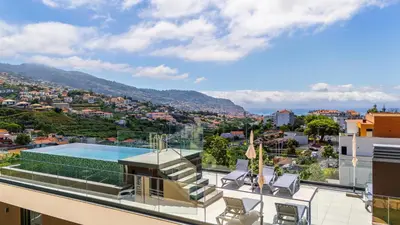 a balcony with a view of a city and a swimming pool at Casa da Ilha in Funchal