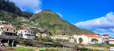 a group of houses on a hill with a mountain at The Jolie - Porto Moniz Central Studios in Porto Moniz