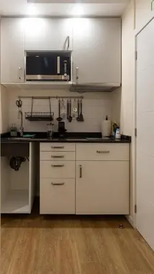 a kitchen with white cabinets and a microwave at The Jolie - Porto Moniz Central Studios in Porto Moniz