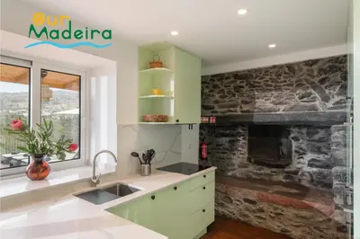 a kitchen with green cabinets and a stone fireplace at Tranquil Villa Close to Facilities - NatureScape in Prazeres