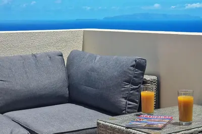 a couch and two glasses of orange juice on a table at Desertas Vista Ninho by LovelyStay in Gaula