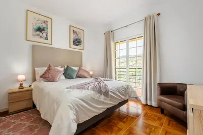 a bedroom with a bed and a chair and a window at Por Do Sol in Calheta