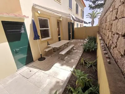 a patio with a table and a bench next to a building at Sea & Sand Guest House in Porto Santo