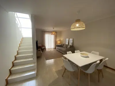a dining room and living room with a table and stairs at Villas Dragoeiro in Porto Santo