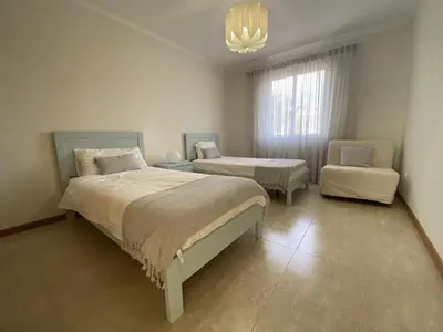 a bedroom with two beds and a chair and a chandelier at Villas Dragoeiro in Porto Santo