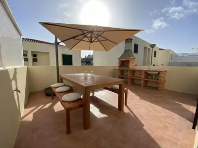 a patio with a wooden table and an umbrella at Villas Dragoeiro in Porto Santo