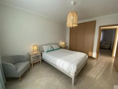 a bedroom with a bed and a chair and a lamp at Villas Dragoeiro in Porto Santo