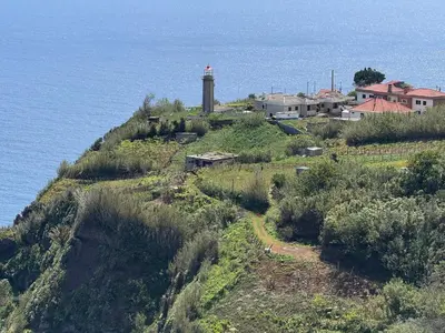 a lighthouse on a hill next to the ocean at Casa do Farol Guest House in São Jorge