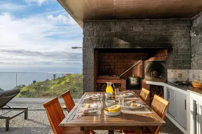 a dining room with a table and a fireplace at With pool and sea view - Vila da Ribeira da Vaca in Calheta