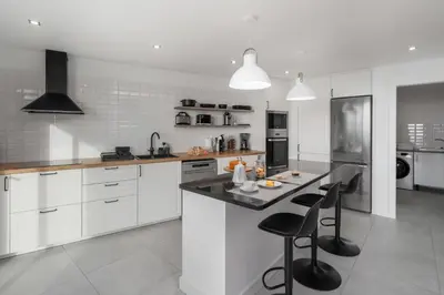a kitchen with white cabinets and a counter with stools at With pool and sea view - Vila da Ribeira da Vaca in Calheta