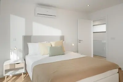 a white bedroom with a large bed with white walls at With pool and sea view - Vila da Ribeira da Vaca in Calheta