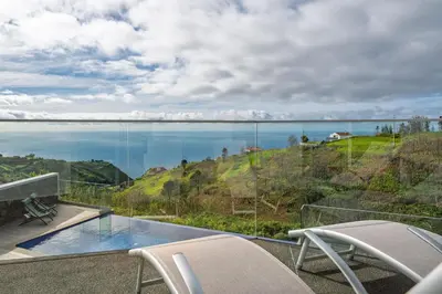 a balcony with chairs and a view of the water at With pool and sea view - Vila da Ribeira da Vaca in Calheta