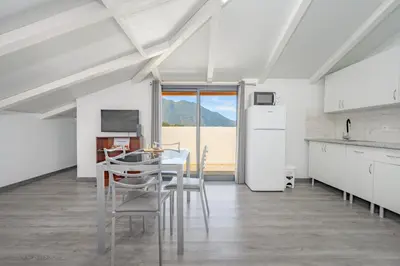 a kitchen with white cabinets and a table and chairs at Casa Vale da Laurissilva in São Vicente