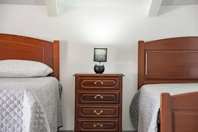 a bedroom with two beds and a dresser with a lamp on it at Casa Vale da Laurissilva in São Vicente