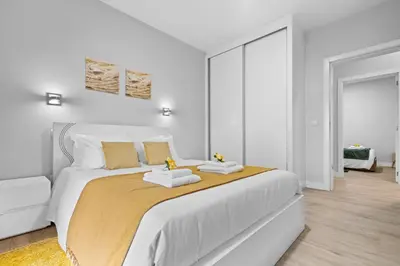 a white bedroom with a large bed with two towels at River Side in Senhora do Rosário