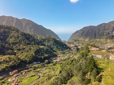 an aerial view of a valley with mountains and the ocean at River Side in Senhora do Rosário