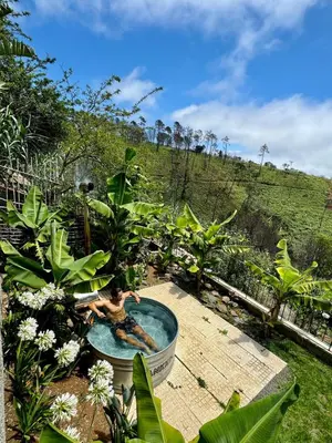 a man in a bath tub in a garden at NEW! Nature Paradise with Ocean View & Hot Tubs in Fajã da Ovelha