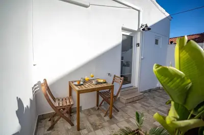 a small patio with a wooden table and chairs at Cozy Old Town Apartment with Sunny Terrace in Vila do Bispo