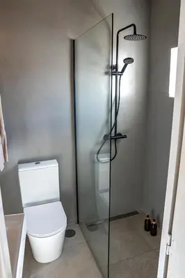 a bathroom with a toilet and a glass shower stall at Cozy Old Town Apartment with Sunny Terrace in Vila do Bispo