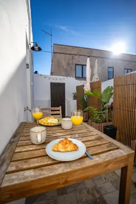 a table with a plate of food and glasses of orange juice at Cozy Old Town Apartment with Sunny Terrace in Vila do Bispo