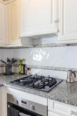 a stove top oven in a kitchen with white cabinets at Casa Maisie Apartment in Burgau