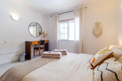 a white bedroom with a bed and a desk at Casa Maisie Apartment in Burgau