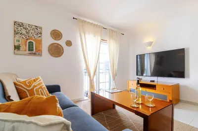 a living room with a blue couch and a tv at Casa Maisie Apartment in Burgau