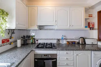 a kitchen with white cabinets and a stove top oven at Casa Maisie Apartment in Burgau