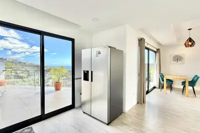 a stainless steel refrigerator in a living room with a table at Anna-Marie House in Ponta do Sol