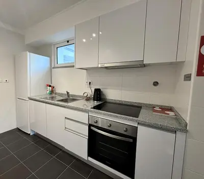 a kitchen with white cabinets and a sink at A SELVA T2 in Caniço in Caniço
