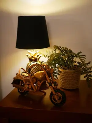 a table with a lamp and a toy motorcycle on it at A SELVA T2 in Caniço in Caniço