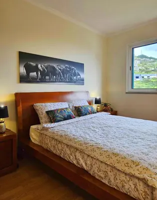 a bedroom with a bed and a large window at A SELVA T2 in Caniço in Caniço