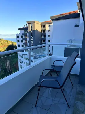a balcony with two chairs and a view of the ocean at A SELVA T2 in Caniço in Caniço