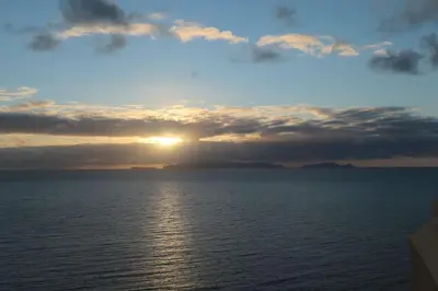 a sunset over the ocean with the sun setting at Aylevarroo Penthouse in Caniço