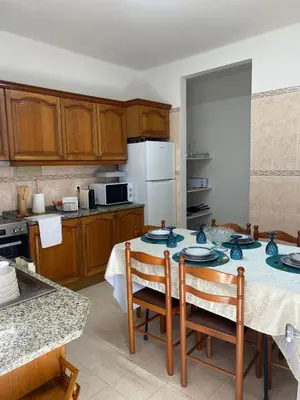 a kitchen with a table with chairs and a refrigerator at Comboio Funchal in Funchal