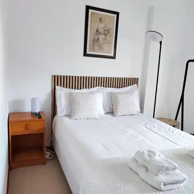 a bedroom with a white bed with a wooden night stand at Sol I in Funchal