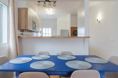 a blue table with six chairs and a kitchen at Casa Mieiro - Porto Santo in Porto Santo