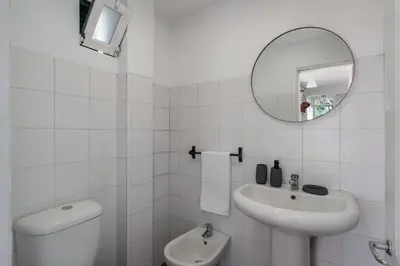 a white bathroom with a sink and a mirror at Retiro do Artista art and views over the valley in São Vicente