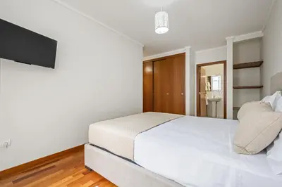 a bedroom with a white bed and a television at Nara by KAAMAH in Santa Cruz