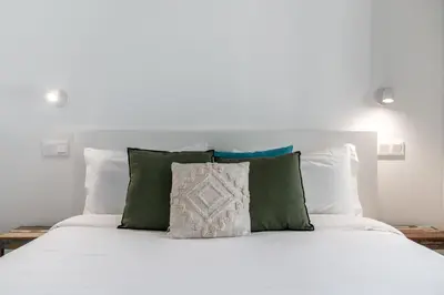 a white bed with green and white pillows at Acqua Residence VII - Luxury 3BR in Funchal in Funchal