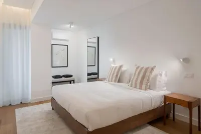 a white bedroom with a large bed and a table at Acqua Residence VII - Luxury 3BR in Funchal in Funchal