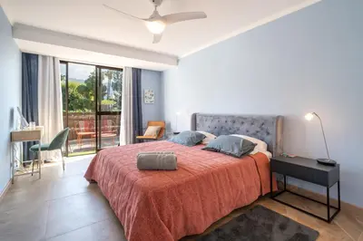 a bedroom with a bed with a red blanket and a desk at Magnolia Terrace by Amazing Madeira in Funchal