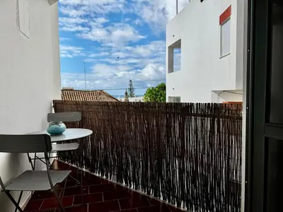 a table and chairs on a balcony with a fence at O Mar a dois minutos in Luz