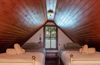 a attic bedroom with two beds and a window at Portas da Levada B by Rent-a-key in São Vicente