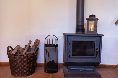 a room with a stove and a basket of wood at Portas da Levada B by Rent-a-key in São Vicente