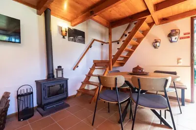 a room with a wood stove and a table and chairs at Portas da Levada B by Rent-a-key in São Vicente