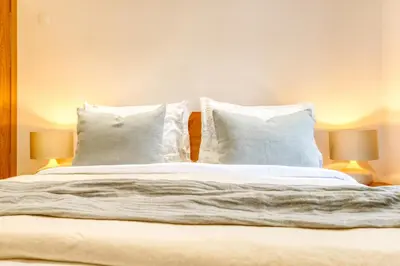 a bedroom with a bed with white pillows and two lamps at Casa do Pinheiro II, a Home in Madeira in São Vicente